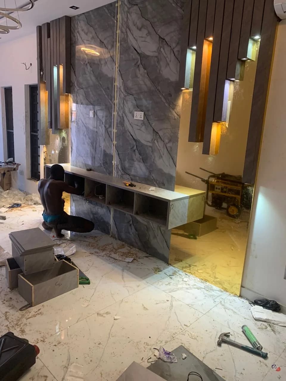 A fitter kneeling to set a floating console into a marble and brass feature wall.