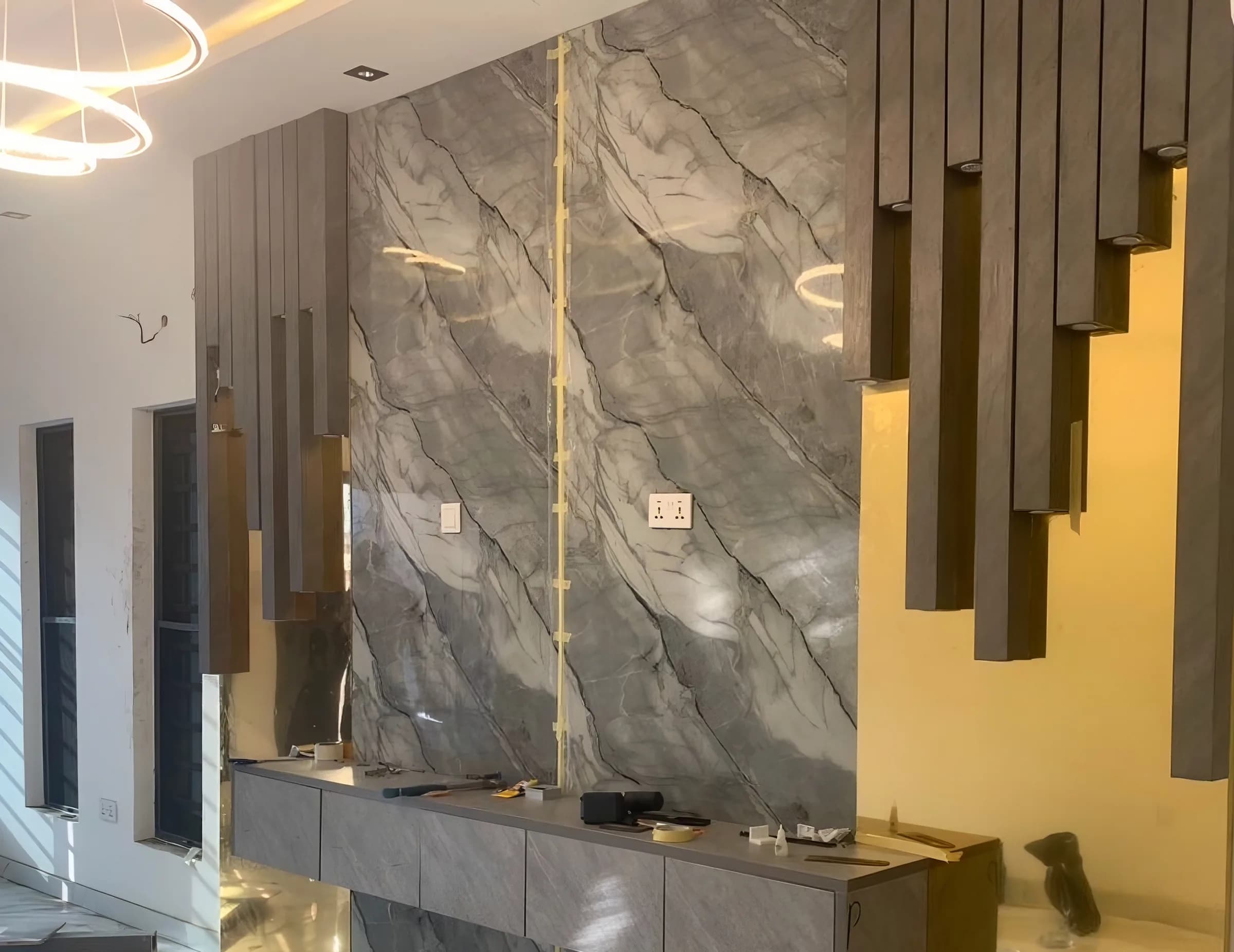 A bespoke commissioned interior under construction — a floating console going in against a marble feature wall.