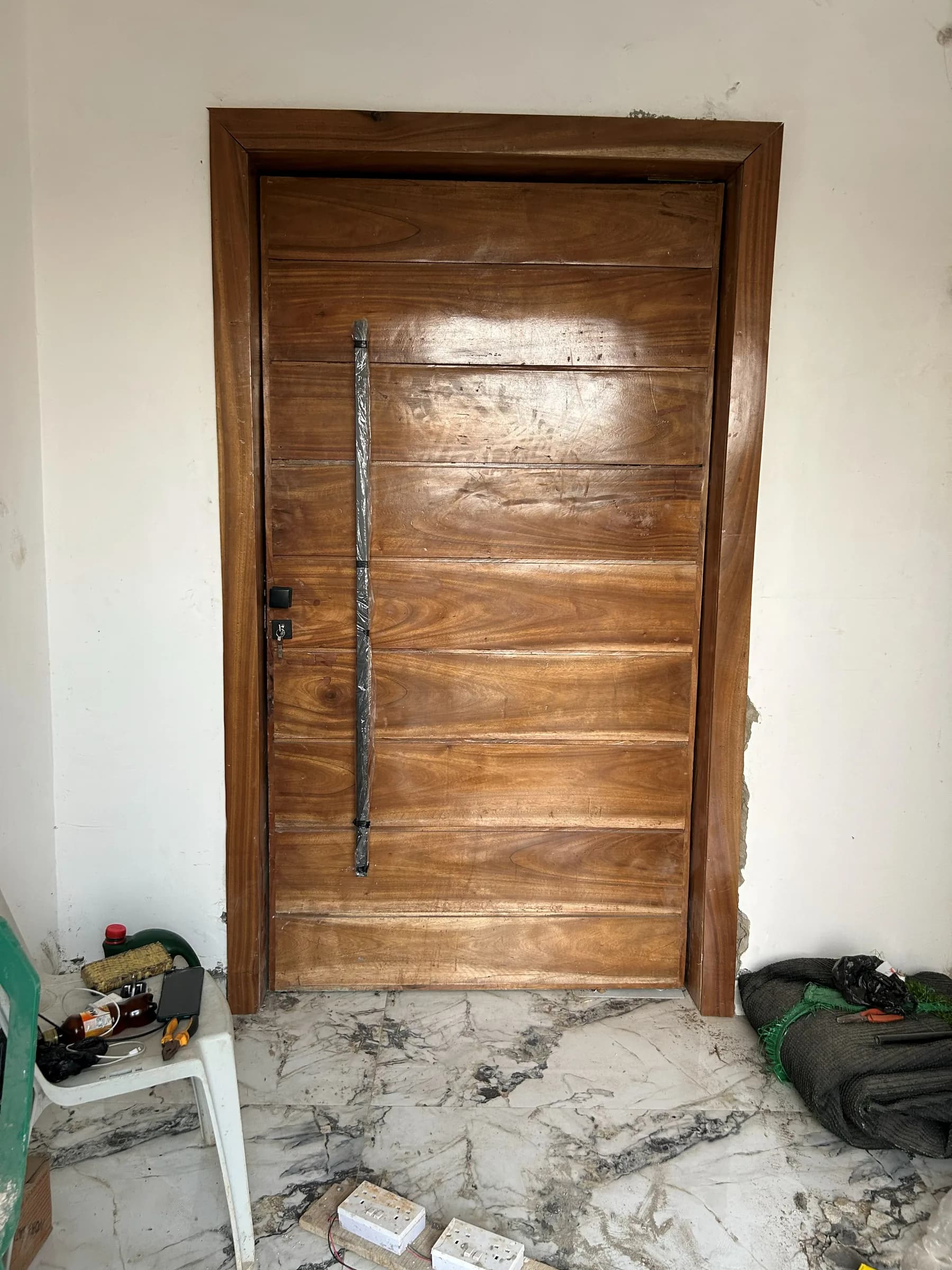 Solid timber door hung in a wooden frame, its long pull handle still taped for protection.