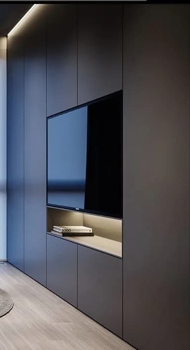 Matte charcoal built-in media wall with a recessed TV and backlit oak shelf above pale oak flooring.