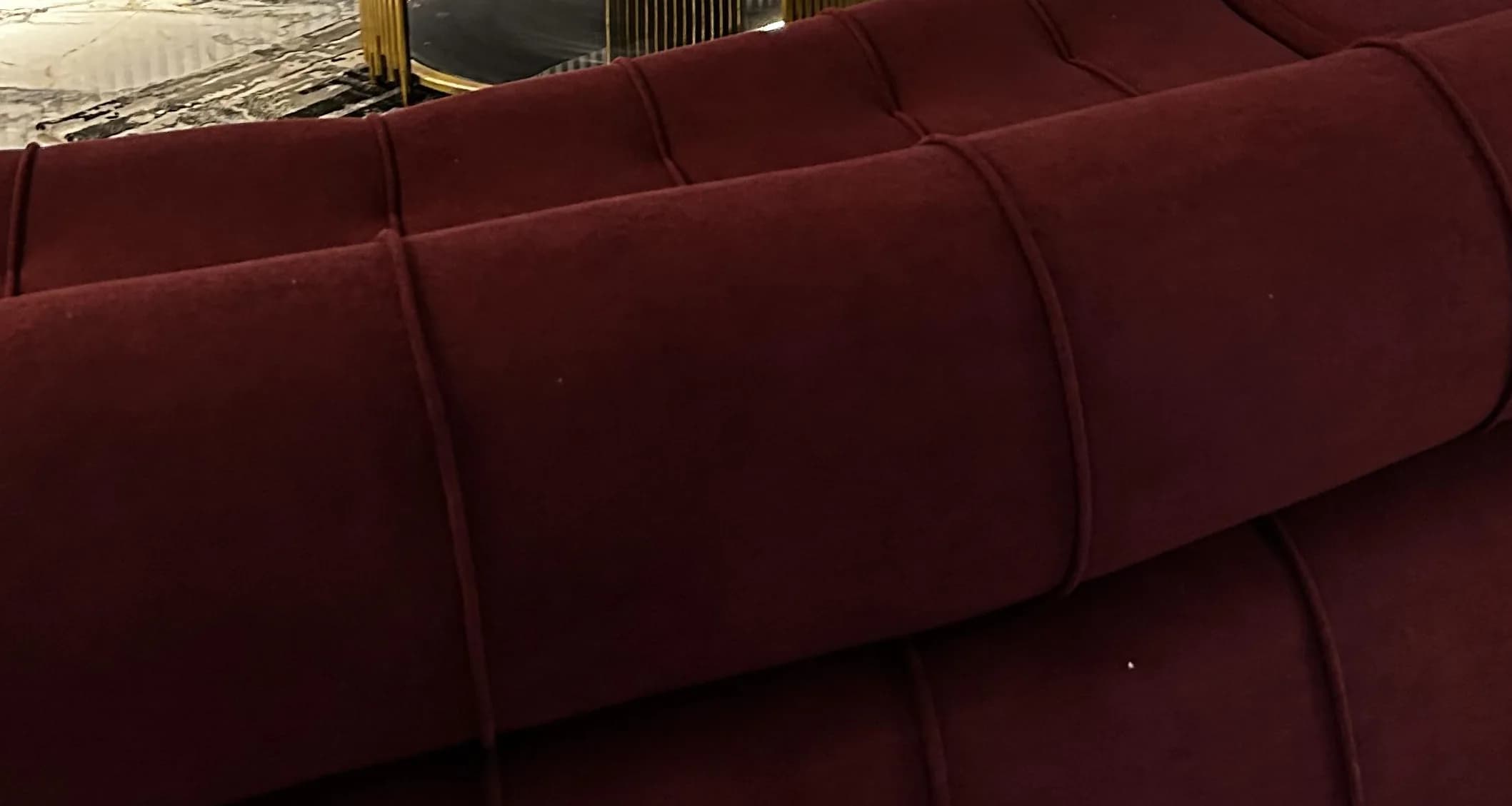 Close-up of the Helix sofa's channelled burgundy velvet bolster and seat flutes.