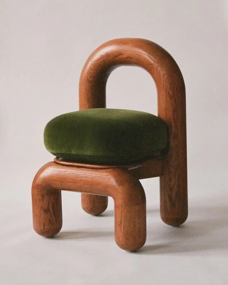 Rounded oak chair with arched backrest and olive-green velvet seat on a cream backdrop