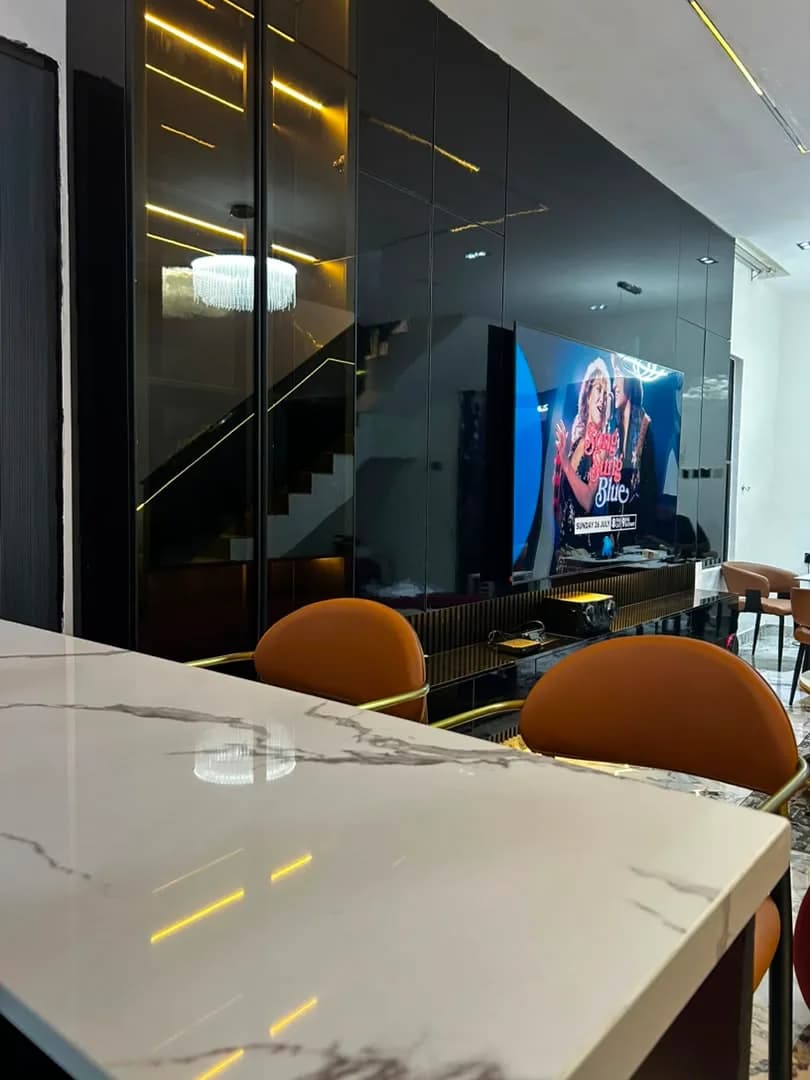 Fluted dark media console and tinted glass partition wall seen past a white marble counter.