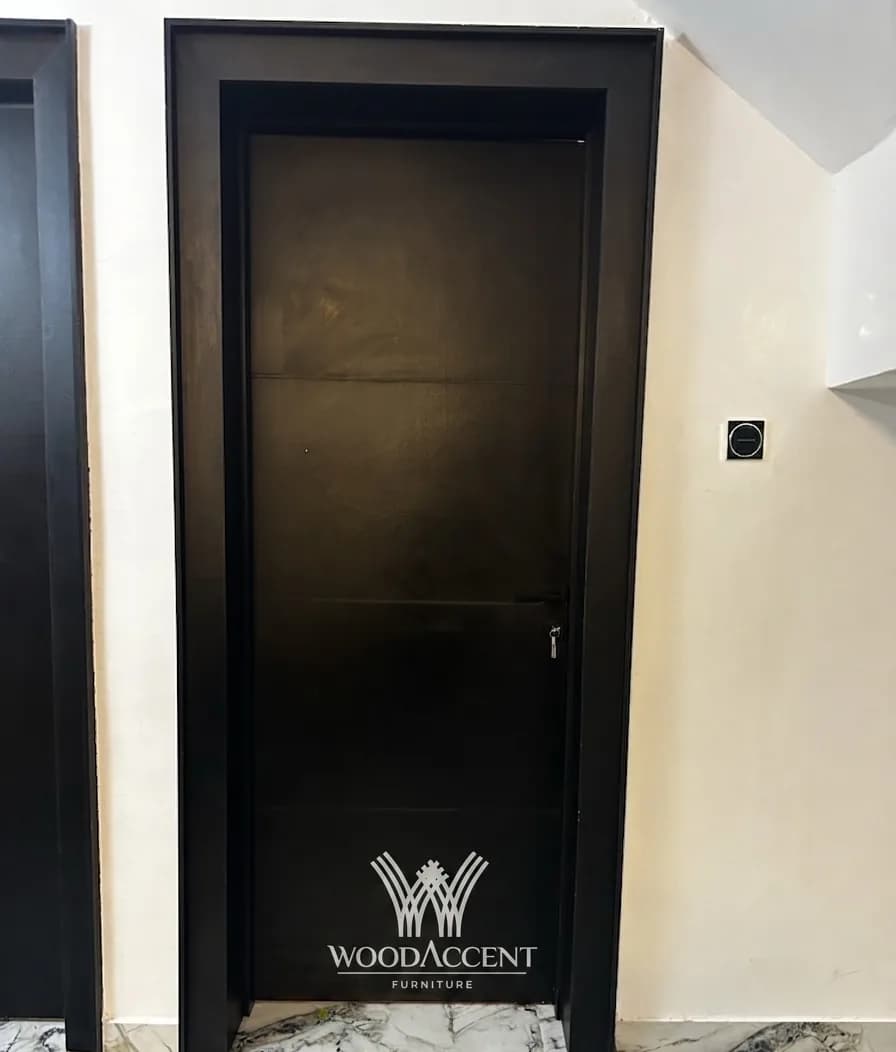 Black panelled door in a matching dark frame against a pale hallway wall.
